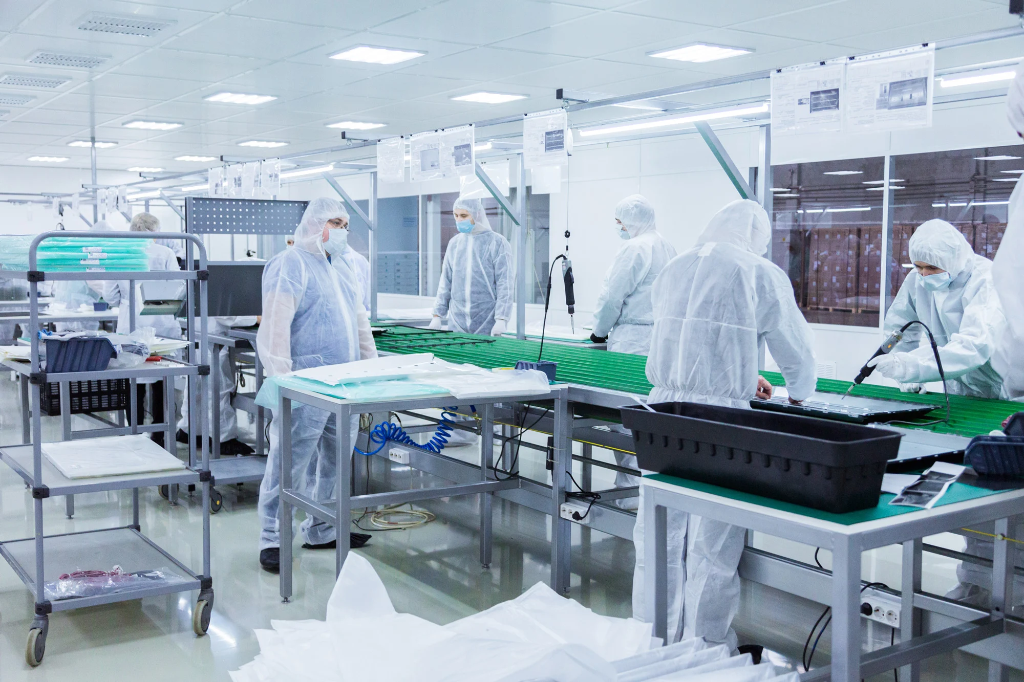Workers wearing protective cleanroom suits on electronic assembly line in Disrupt-X HSEQ manufacturing facility
