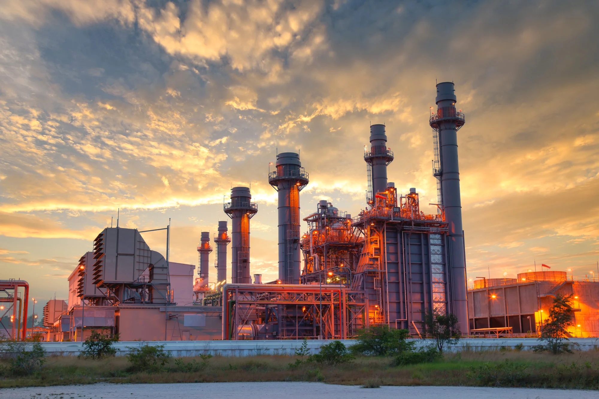 Gas turbine power generation plant with exhaust stacks at sunset managed for energy safety by Disrupt-X HSEQ