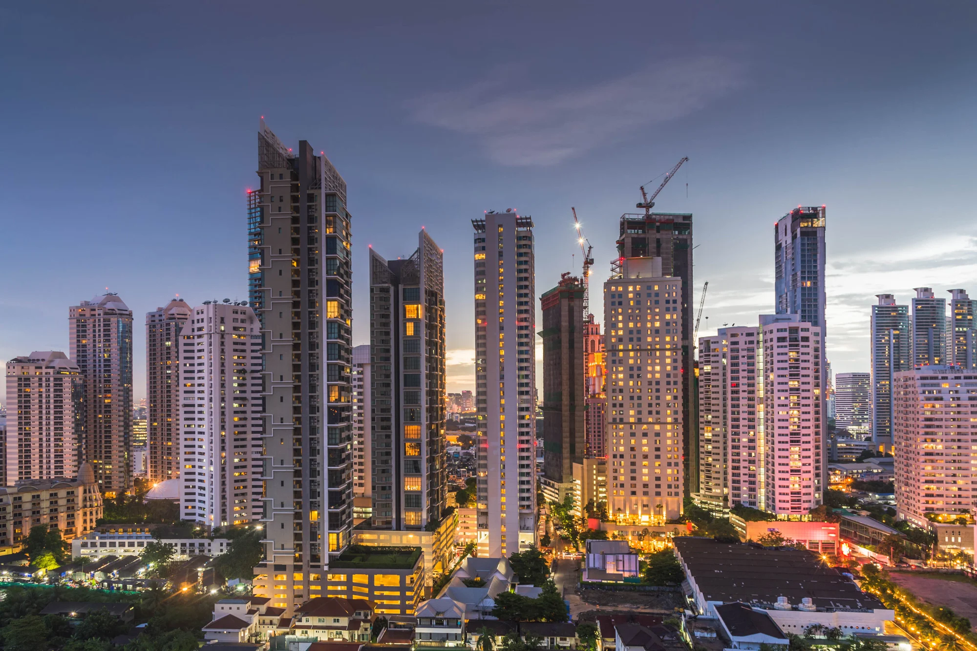 Illuminated modern high-rise city skyscrapers at night managed for urban environmental compliance and building safety